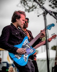 two men playing blue electric guitars in front of a crowd